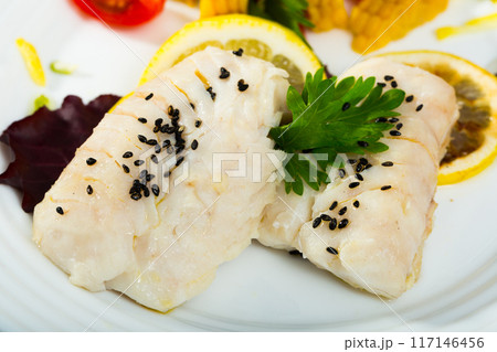 Closeup of steamed hake with tomatoes, corn and lemon 117146456