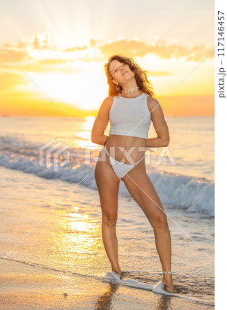 Young woman in thong and top posing standing on beach 117146457