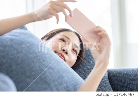 ソファーで横になってスマホを見る女性 ソファーで横になってスマホを見る女性 117146467