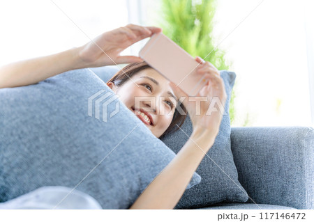 ソファーで横になってスマホを見る女性 ソファーで横になってスマホを見る女性 117146472