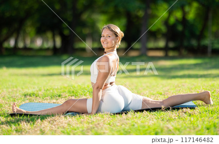 Fit girl performing front split in summer park Fit girl performing front split in summer park 117146482
