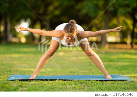 Girl in park on green grass of lawn performs Himavanasana Girl in park on green grass of lawn performs Himavanasana 117146546