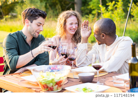 Having a joyful garden party with wine, laughs, and friends in a relaxed outdoor setting 117148194