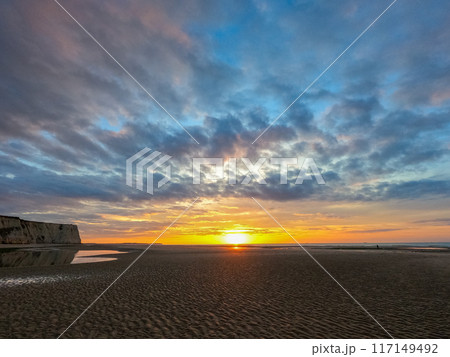 Stunning beach sunrise with dramatic clouds, vibrant colors reflecting on the water 117149492