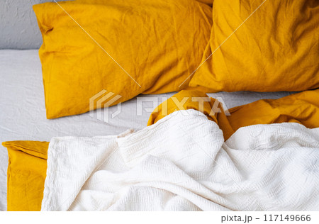 Cozy bed with yellow pillows and white blanket in modern bedroom. Cozy bed with yellow pillows and white blanket in modern bedroom. 117149666