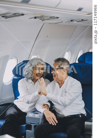 .A mature couple enjoys a plane ride sitting near the window. They looked out into the sky. Immerse yourself in the scenery and excitement of the journey. To create precious memories together 117149966