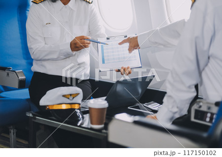 Professional pilot woman in uniform has teamwork meeting for success flight in aviation business. Young female captain instructor sitting in office and working or training commercial airline crew. 117150102
