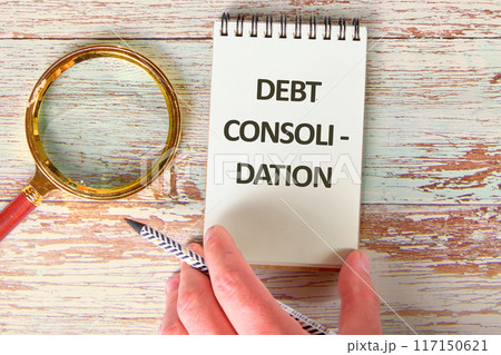 Business concept. DEBT CONSOLIDATION words in the notebook next to the magnifying glass 117150621