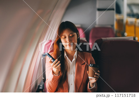 Attractive Asian female passenger of airplane sitting in comfortable seat while working laptop and tablet with mock up area using wireless connection. Travel in style, work with grace. Attractive Asian female passenger of airplane sitting in comfortable seat while working laptop and tablet with mock up area using wireless connection. Travel in style, work with grace. 117151718