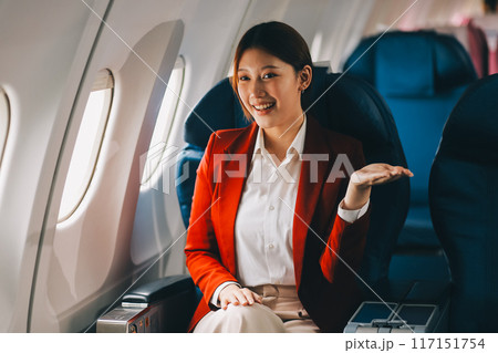 A young Asian woman, seated as an airplane passenger, contemplates dollar bills, reflecting on lucrative opportunities and aspirations towards billionaire status. A young Asian woman, seated as an airplane passenger, contemplates dollar bills, reflecting on lucrative opportunities and aspirations towards billionaire status. 117151754