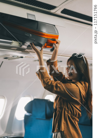 Female tourist packing her luggage in the airplane cabin. 117151766