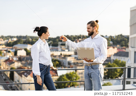 Couple discussing new house keys on city rooftop Couple discussing new house keys on city rooftop 117152243