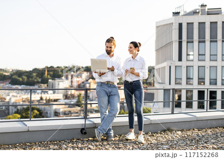 Business colleagues discussing work on rooftop with laptop 117152268
