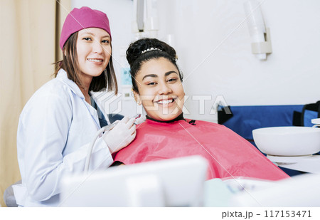 Portrait of smiling dentist with female patient in medical office, Female dentist with smiling female patient looking at camera, Professional dentist with female patient in office 117153471