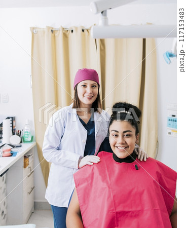 Portrait of dentist with patient smiling at camera in office, Female dentist with satisfied patient smiling at camera, Female dentist with patient smiling friendly Portrait of dentist with patient smiling at camera in office, Female dentist with satisfied patient smiling at camera, Female dentist with patient smiling friendly 117153483