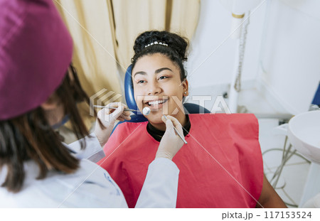 Close up of female dentist doing dental checkup to smiling patient, Patient lying on chair smiling at dentist, Dentist doing dental checkup to female patien Close up of female dentist doing dental checkup to smiling patient, Patient lying on chair smiling at dentist, Dentist doing dental checkup to female patien 117153524