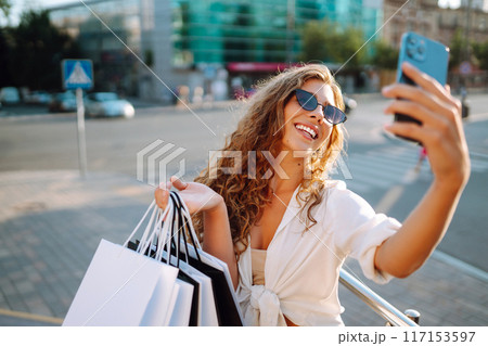 Stylish young woman shopping with phone on street. Woman is using mobile phone. Active lifestyle 117153597