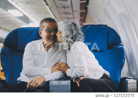 .A mature couple enjoys a plane ride sitting near the window. They looked out into the sky. Immerse yourself in the scenery and excitement of the journey. To create precious memories together 117153775