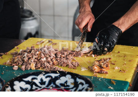 male chef cut boiled lamb meat with a knife to cook traditional oriental Uzbek pilaf in restaurant in Tashkent in Uzbekistan close up male chef cut boiled lamb meat with a knife to cook traditional oriental Uzbek pilaf in restaurant in Tashkent in Uzbekistan close up 117154190