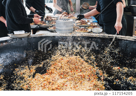 male chefs cook Uzbek pilaf with vegetables in a cauldron in restaurant. Traditional Asian Uzbek cuisine. Central Asian Pilaf Center Besh Qozon in Uzbekistan male chefs cook Uzbek pilaf with vegetables in a cauldron in restaurant. Traditional Asian Uzbek cuisine. Central Asian Pilaf Center Besh Qozon in Uzbekistan 117154205