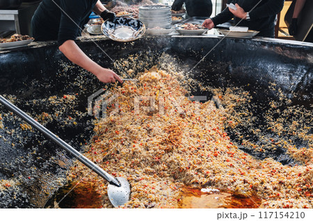 cooking traditional oriental Uzbek pilaf in huge cauldron in the kitchen at the Tashkent Pilaf Center Besh Qozon in Uzbekistan 117154210