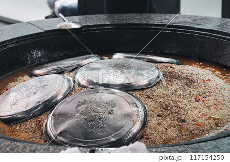 cooking traditional uzbek dish rice pilaf in a cauldron in kitchen of a restaurant in Central Asian pilaf center in Tashkent in Uzbekistan close-up 117154250