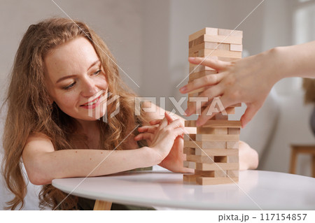 two women playing a board game made of wooden blocks at home, excitement and relaxation, mind development concept, hand motor skills, 117154857