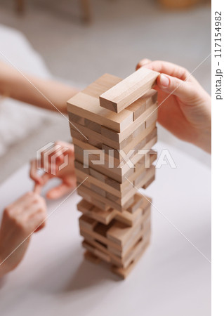 two women playing a board game made of wooden blocks at home, excitement and relaxation, mind development concept, hand motor skills, 117154982