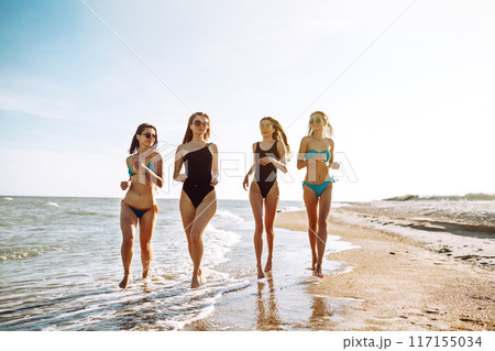 Four young girls having fun on the beach. Group of girlfriends enjoying on beach holiday. Summer lifestyle. 117155034