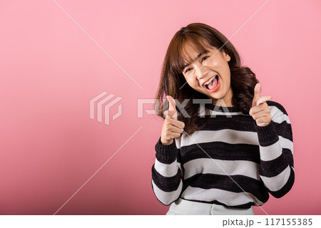 Woman excited smiling makes finger two gun gesture to camera isolated pink background, Happy Asian portrait beautiful young female says you are chosen ll kill you or what up man with cheeky copy space 117155385