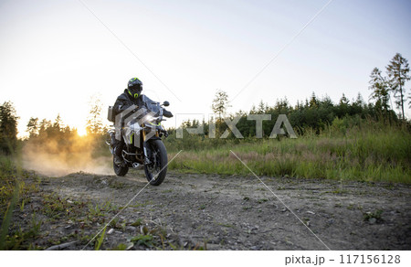 Driver riding motorcycle on empty road during sunset Driver riding motorcycle on empty road during sunset 117156128