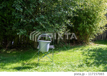 Bucket Hanging On a Metal Chair Back in a Sunlit Urban Garden Bucket Hanging On a Metal Chair Back in a Sunlit Urban Garden 117157065