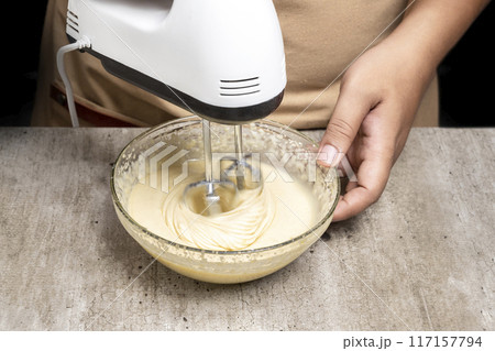 A person is making a cake and has a bowl of flour and sugar on the table 117157794