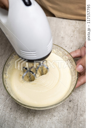 A person is making a cake and has a bowl of flour and sugar on the table 117157795