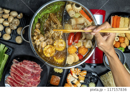 A person is eating food from a large pot of food 117157836