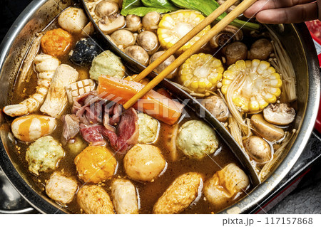 A person is eating food from a bowl with chopsticks 117157868