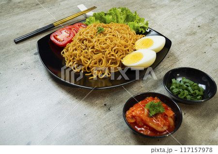 A plate of instant noodles with tomatoes and egg on top 117157978