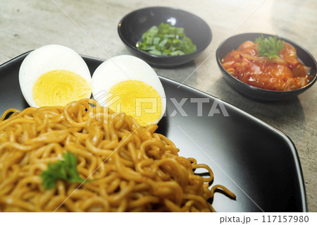 A plate of instant noodles with tomatoes and egg on top 117157980