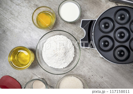 A table with several bowls of ingredients, including flour, sugar, and oil 117158011