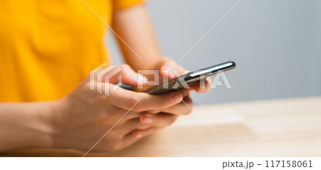 Hand holding smartphone with using social media on internet on table. 117158061
