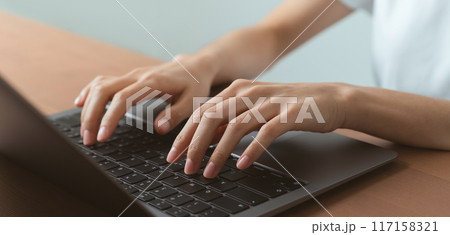 Hand using computer laptop and touching mouse on the table. 117158321