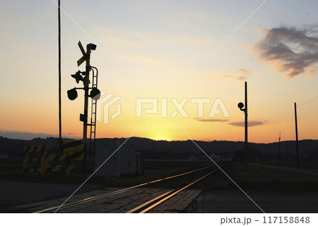 夕陽を浴びて光る線路と警報機 小高い丘のシルエット 夕陽を浴びて光る線路と警報機 小高い丘のシルエット 117158848