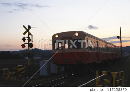 夕陽を浴びて踏切を走り抜けるローカル電車と警報機のシルエット 夕陽を浴びて踏切を走り抜けるローカル電車と警報機のシルエット 117158870