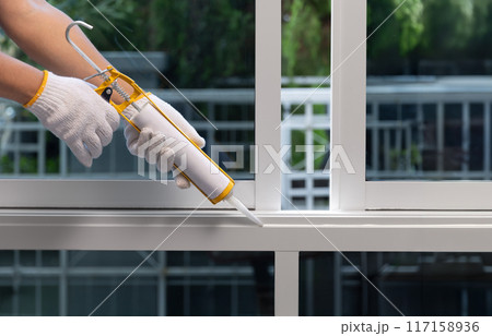Construction worker using silicone sealant caulk for repair leaked inside window frame. 117158936