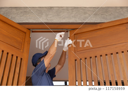Handyman fixing bifold doors sticking or not sliding properly. 117158939