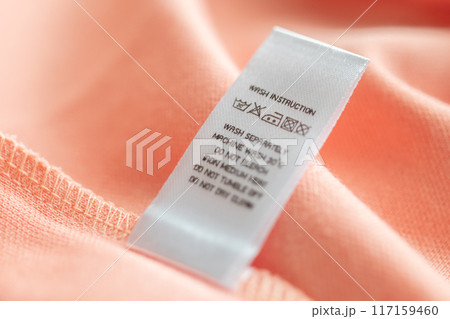 White laundry care washing instructions clothes label on pink cotton shirt 117159460