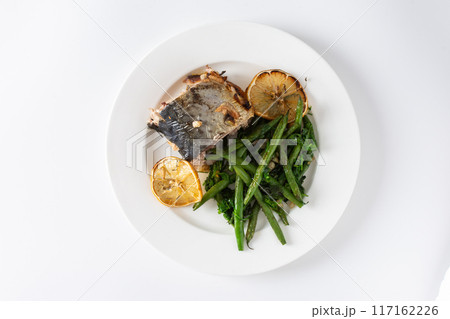 Savor the wholesome flavors of baked green beans with onions and baked mackerel, elegantly plated on a white background, ideal for a nutritious and flavorful dinner Savor the wholesome flavors of baked green beans with onions and baked mackerel, elegantly plated on a white background, ideal for a nutritious and flavorful dinner 117162226