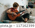 girl playing guitar in home 117162399