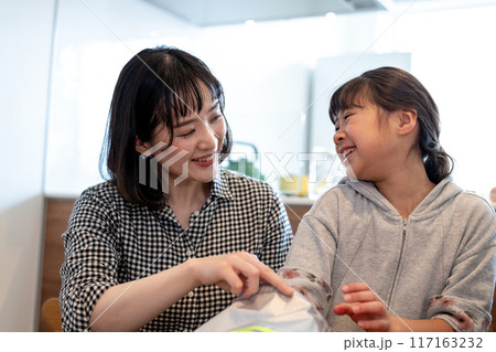 小物入れのナップサックに手を差し入れながら笑い合うお母さんと娘 小物入れのナップサックに手を差し入れながら笑い合うお母さんと娘 117163232
