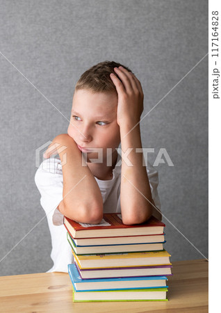 Pensive Young Boy Resting on a Stack of Books. World Dyslexia Awareness Day Pensive Young Boy Resting on a Stack of Books. World Dyslexia Awareness Day 117164828